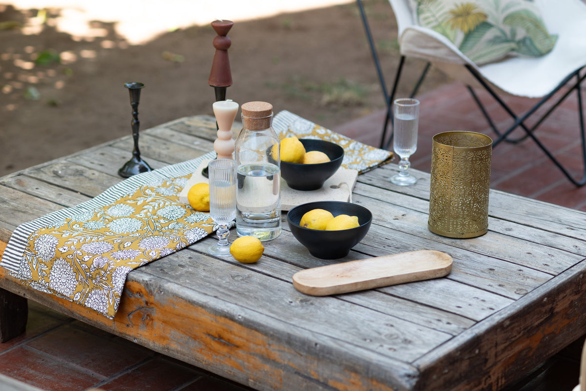 Mesa de madera para terraza con camino de mesa, bowls de cerámica y vasos de vidrio